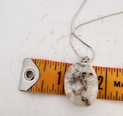 Necklace with a pendant on a ruler for scale on a white background