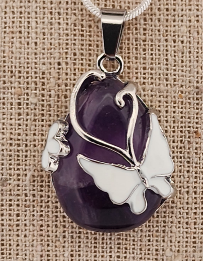 Purple pendant with silver butterfly design on a textured beige background