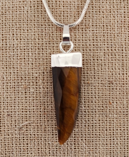 Necklace with a brown and silver pendant on a beige fabric background