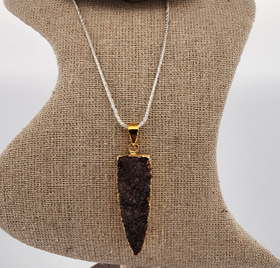 Necklace with a dark pendant on a mannequin bust against a plain background