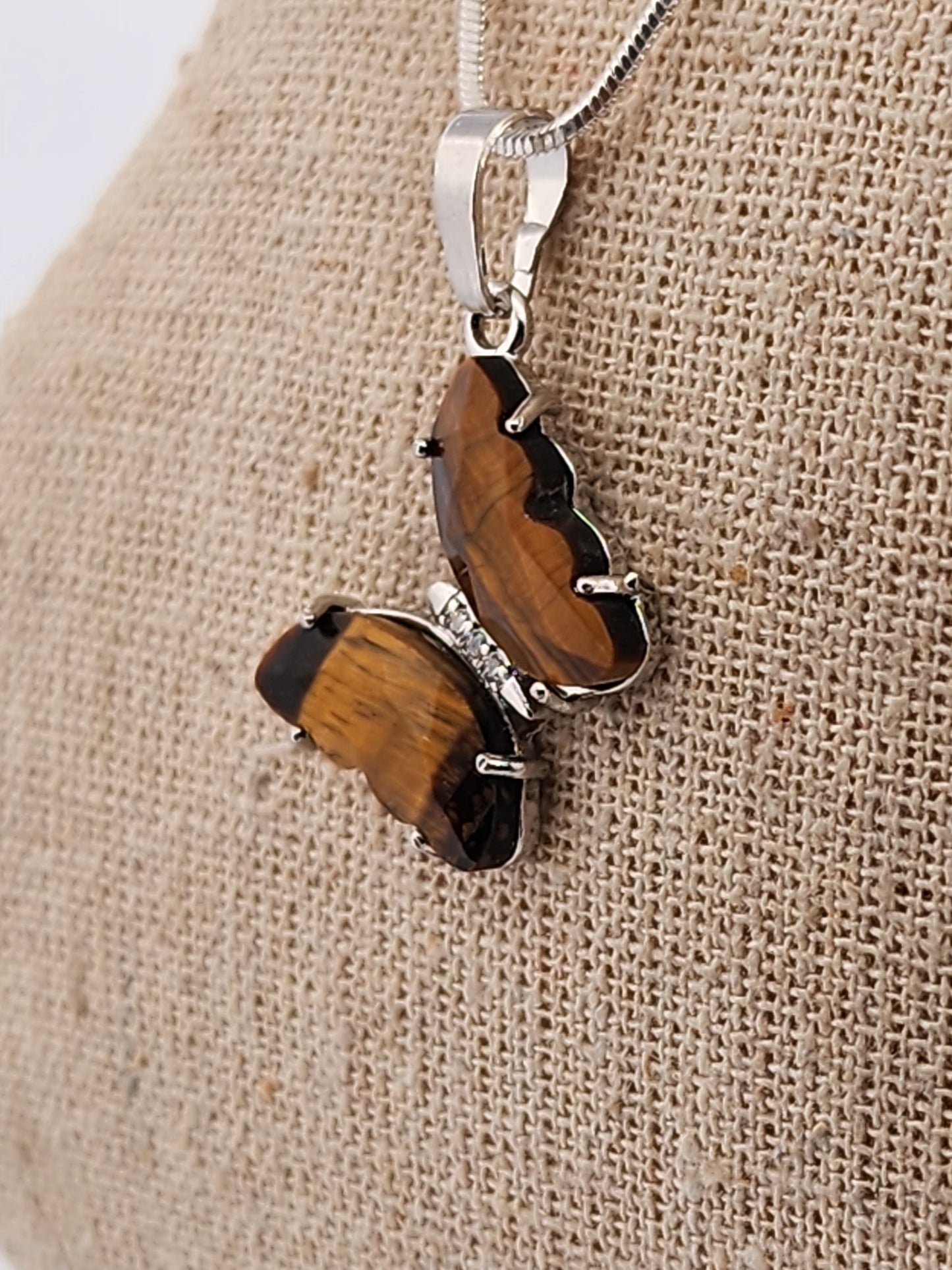 Butterfly-shaped pendant with wooden design on a beige fabric background