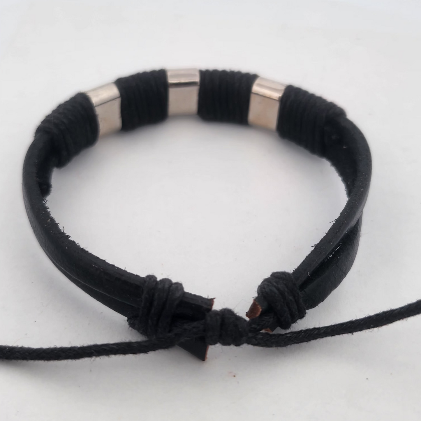Black braided bracelet with silver cylindrical beads on a white background