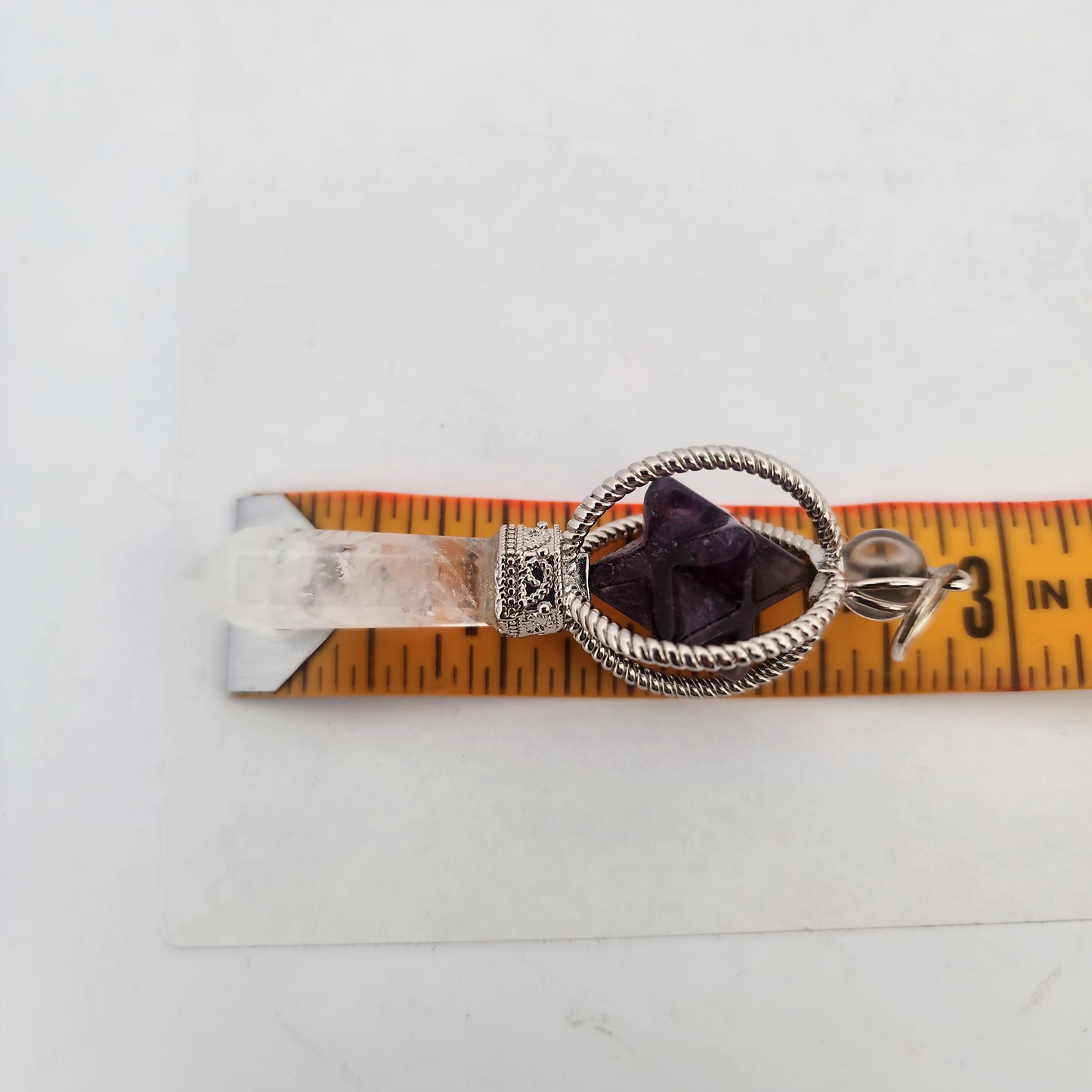 Decorative neckless with purple gemstones on a measuring tape against a white background