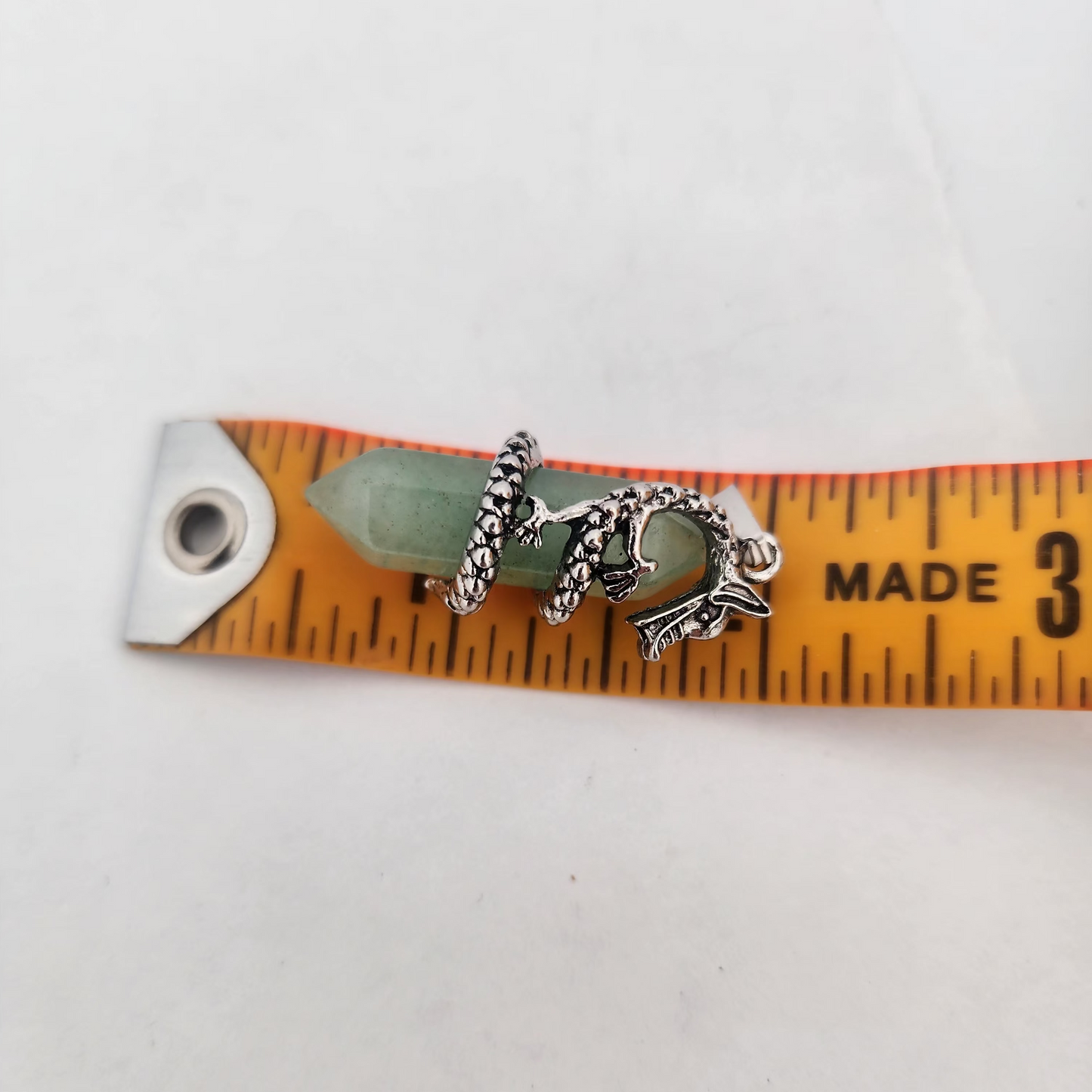 Small silver charm on a ruler for size reference