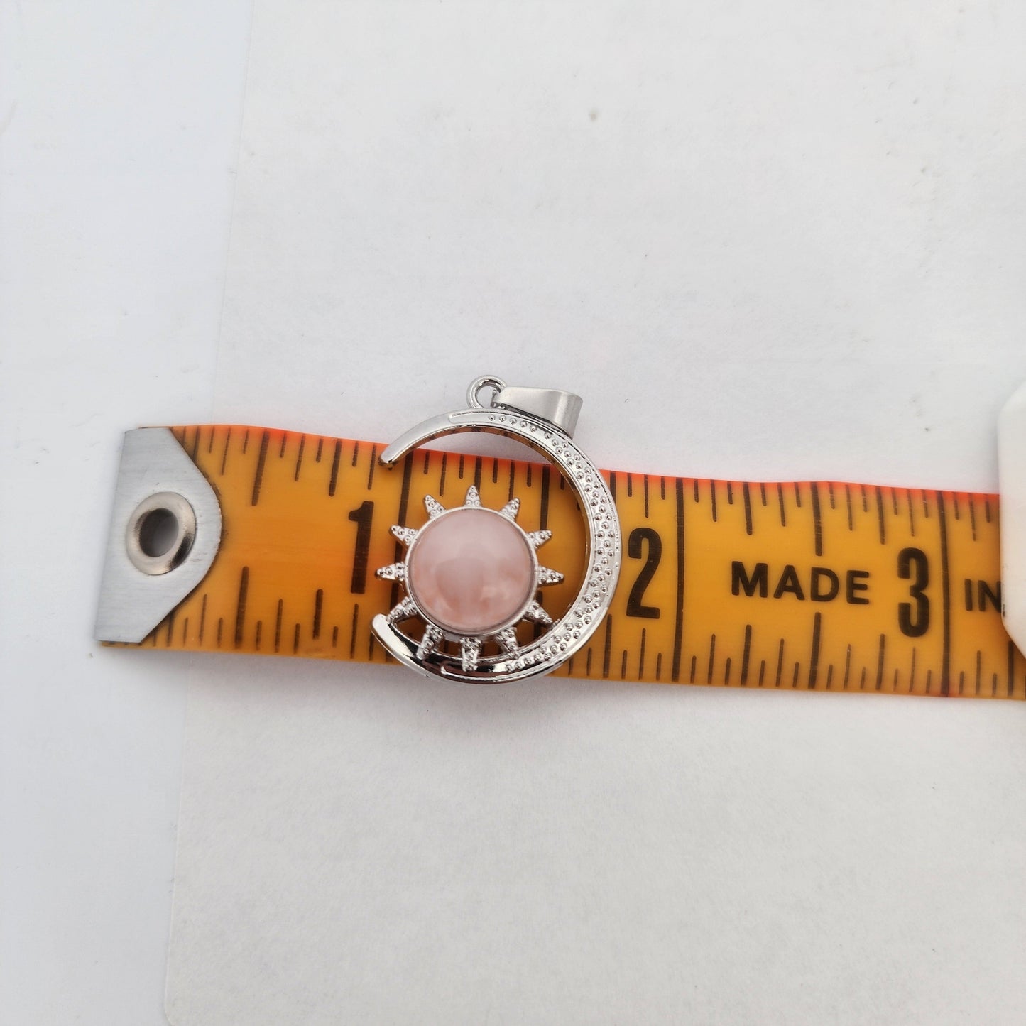 Silver ring with a pink stone on an orange measuring tape against a white background