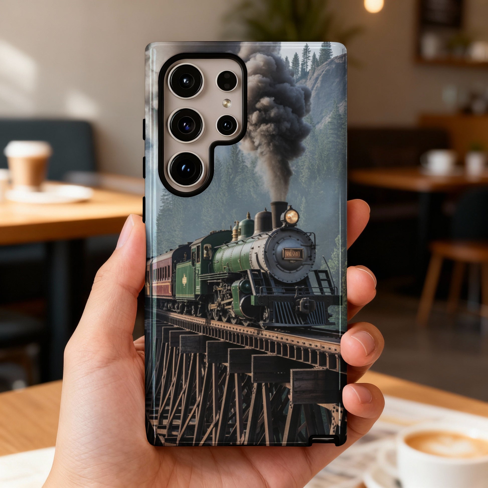Green steam train on wooden trestle bridge with mountains and trees in background.