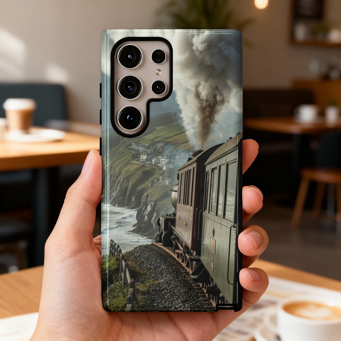 Hand holding smartphone displaying a vintage steam train traveling along a coastal cliffside.