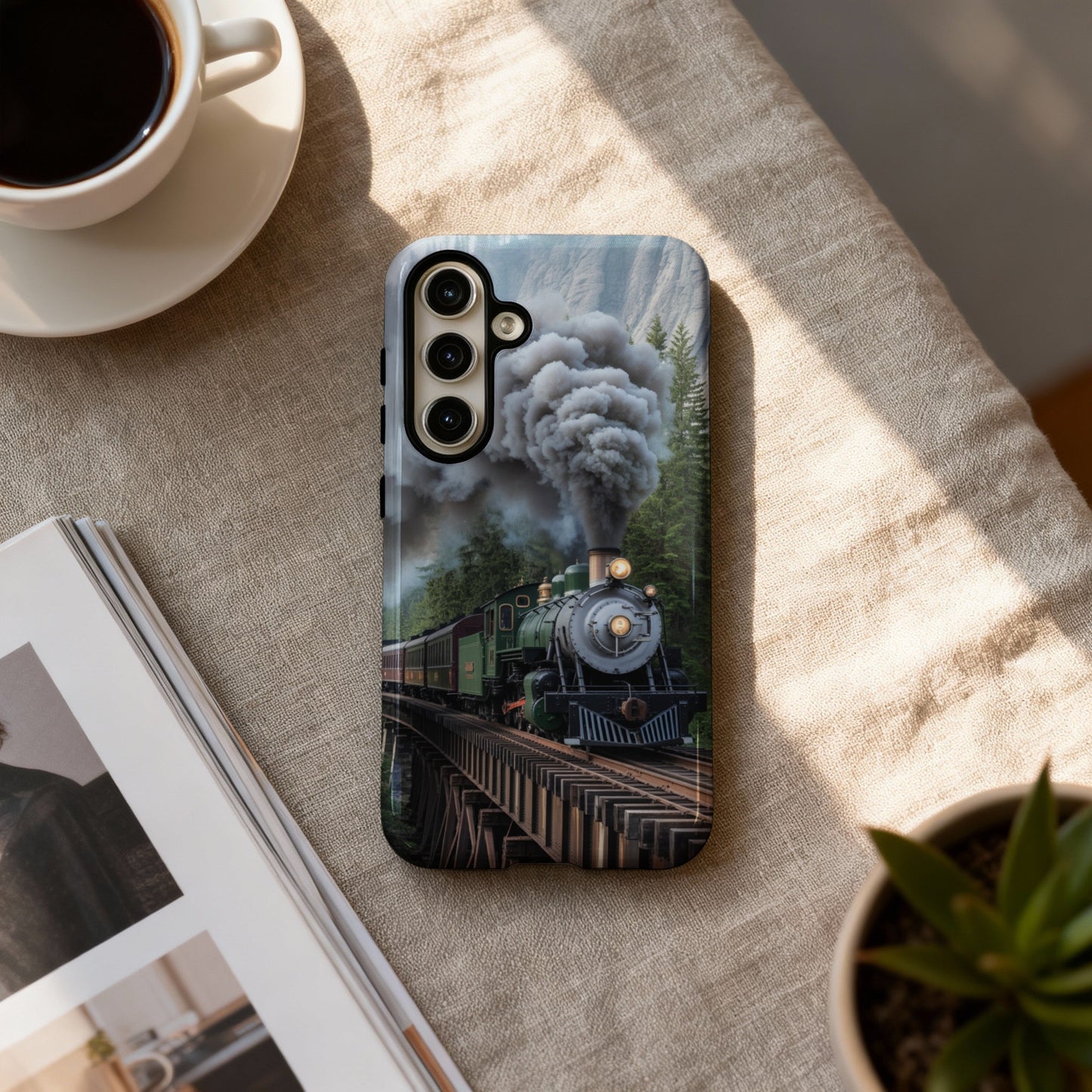 Phone case featuring a steam train on a bridge, with coffee and plant.