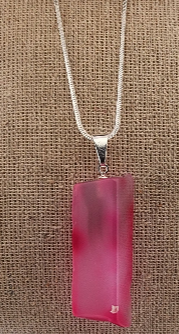 Pink pendant on a silver chain against a brown textured background