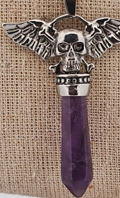 Pendant with skull design and purple crystal on a textured beige background