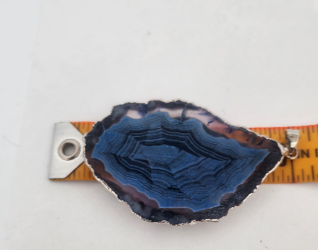 Blue geode crystal with a ruler for scale on a white background