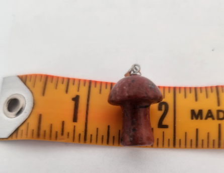 Small mushroom-shaped pendant on a measuring tape for scale