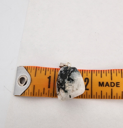 Rock-like pendant on a measuring tape against a white background
