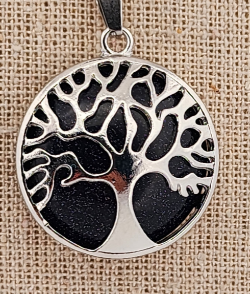 Silver pendant with tree of life design on a textured beige background