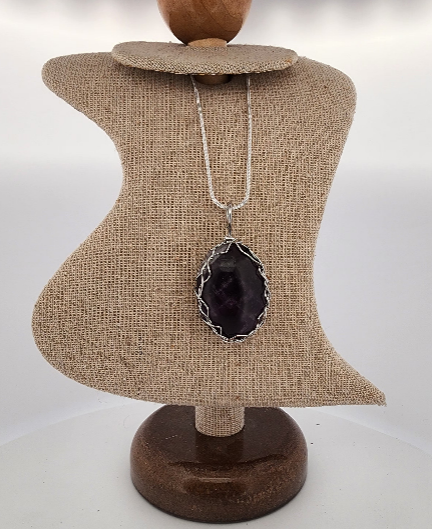 Necklace with a pendant on a textured mannequin bust against a white background