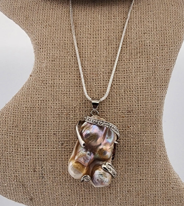 Necklace with a unique pendant on a mannequin bust.