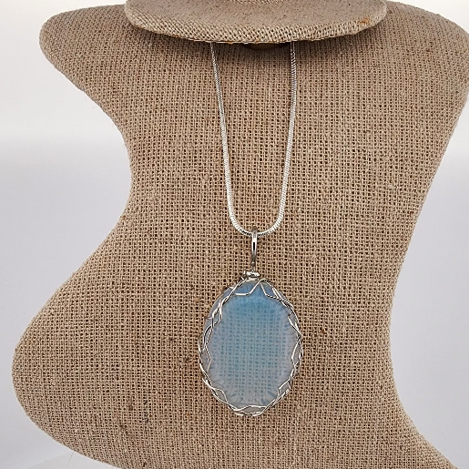 Necklace with a blue pendant on a brown textured stand