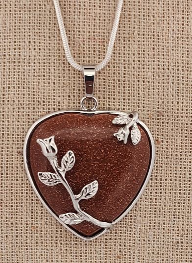 Heart-shaped pendant with floral design on a brown background