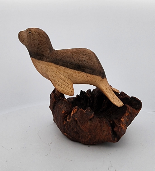 Wooden seal figurine on a textured brown base against a white background