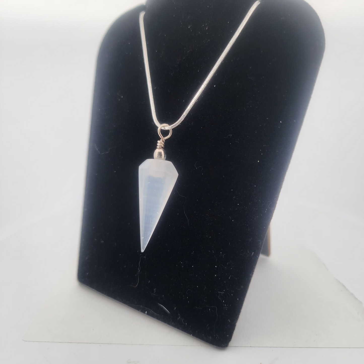 Crystal pendant necklace on a black velvet stand with a white background