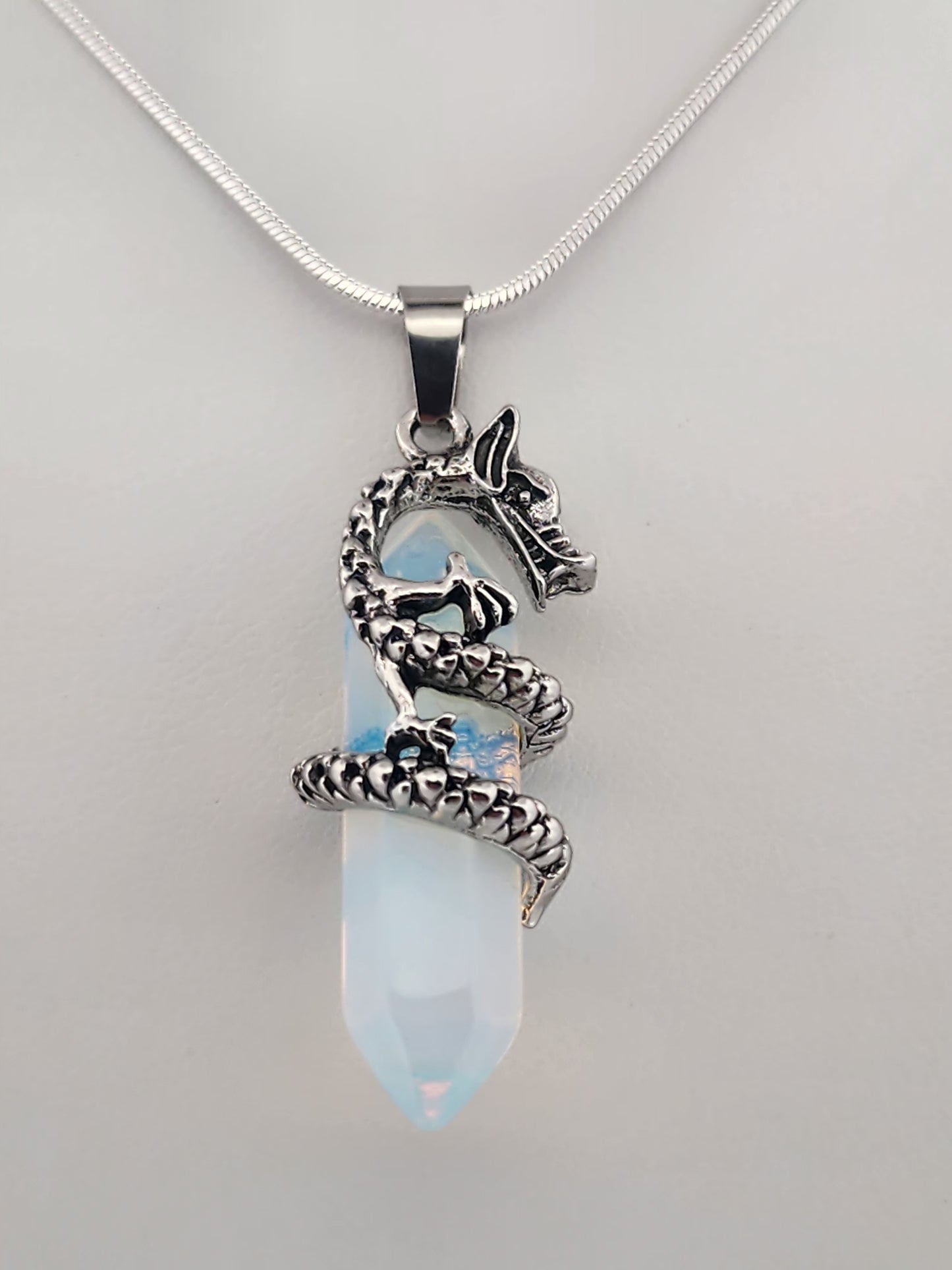 Pendant with snake design on a clear stone and chain against a gray background