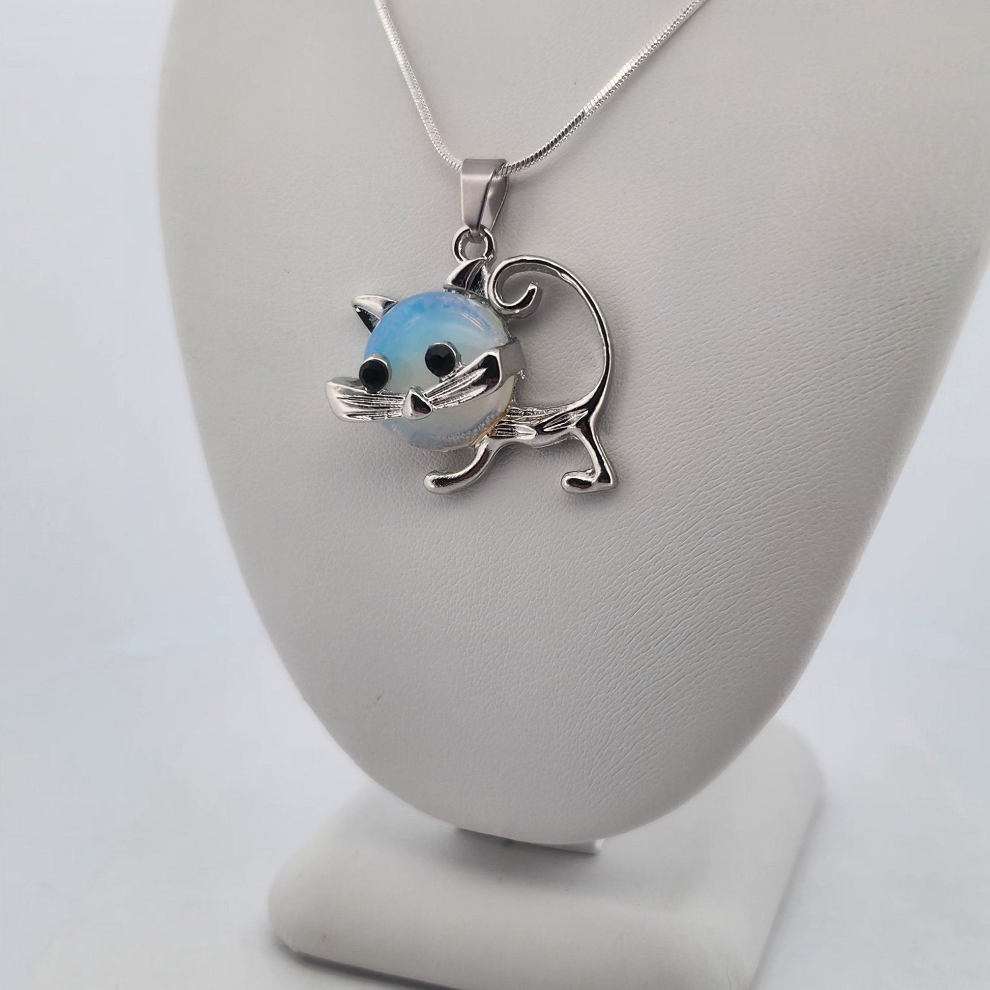 Cat-shaped pendant on a necklace displayed on a white stand