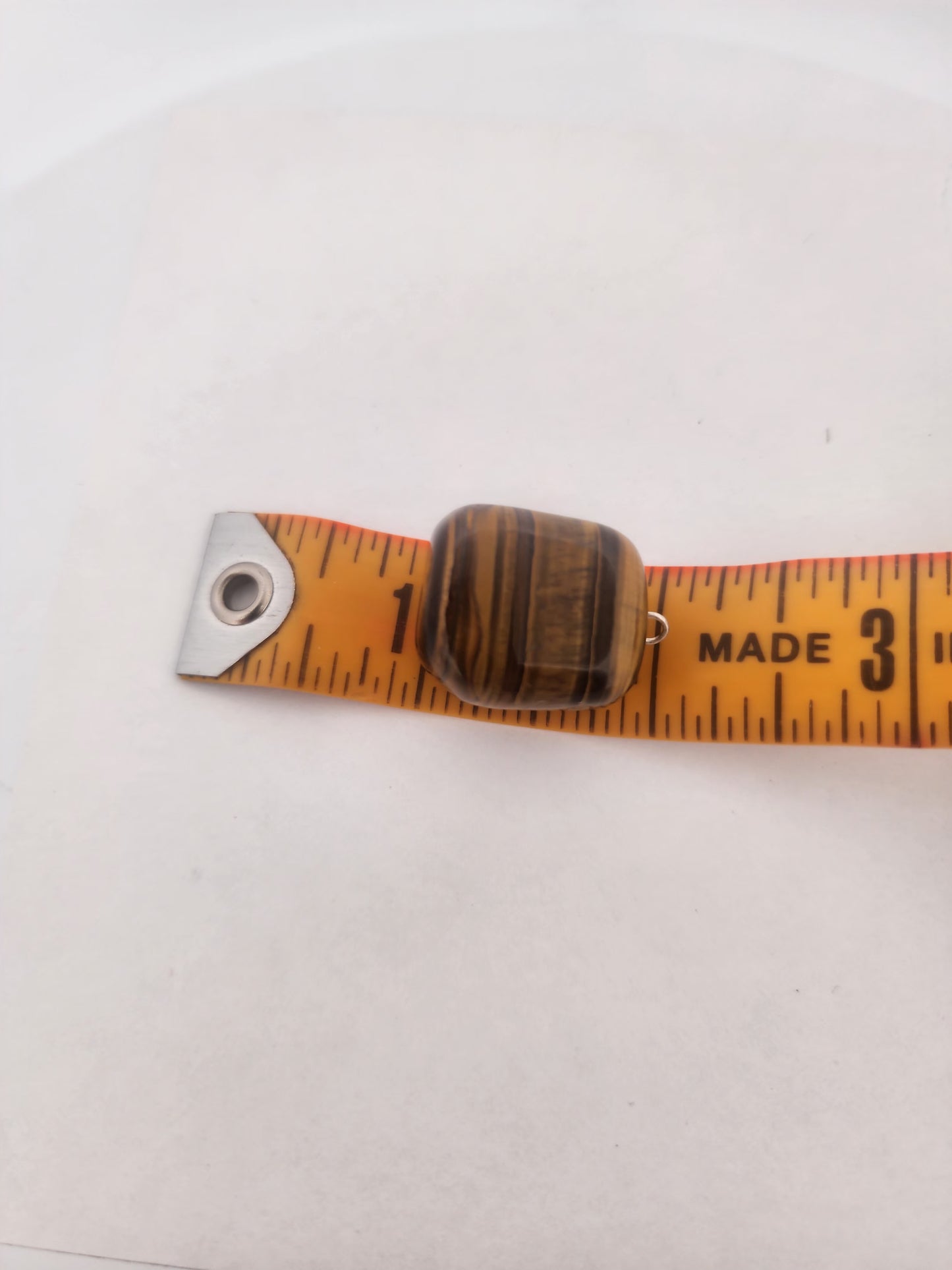 tiger eye stone on a measuring tape against a white background