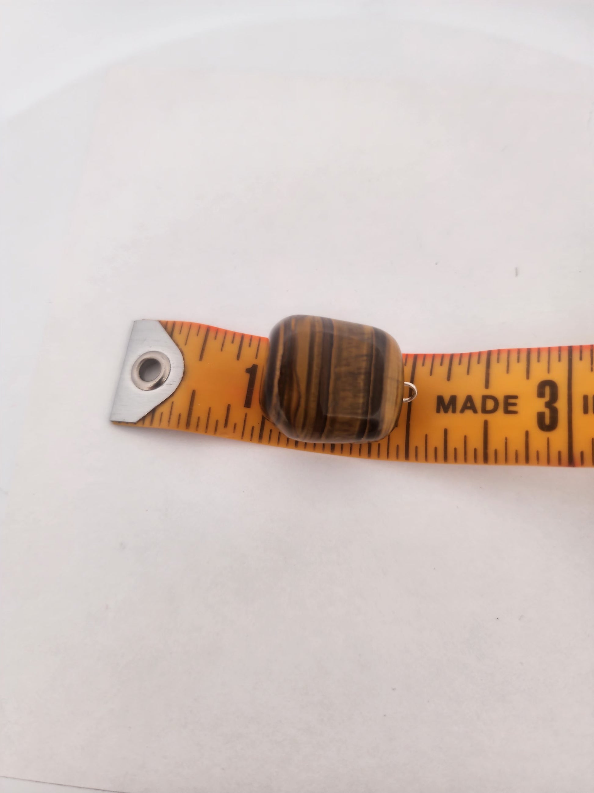  tiger eye stone on a measuring tape against a white background