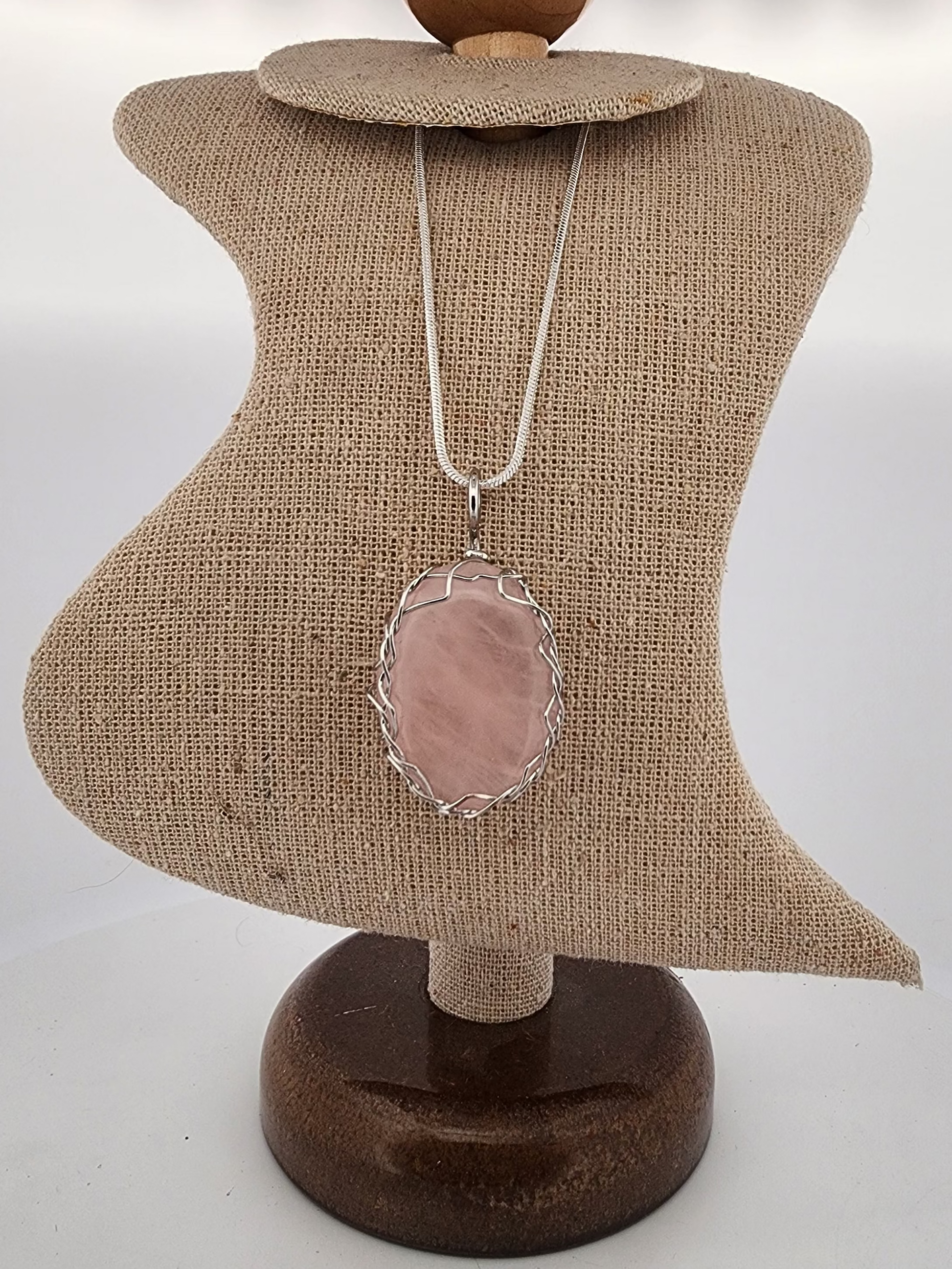 Necklace with a pink pendant on a mannequin bust against a white background