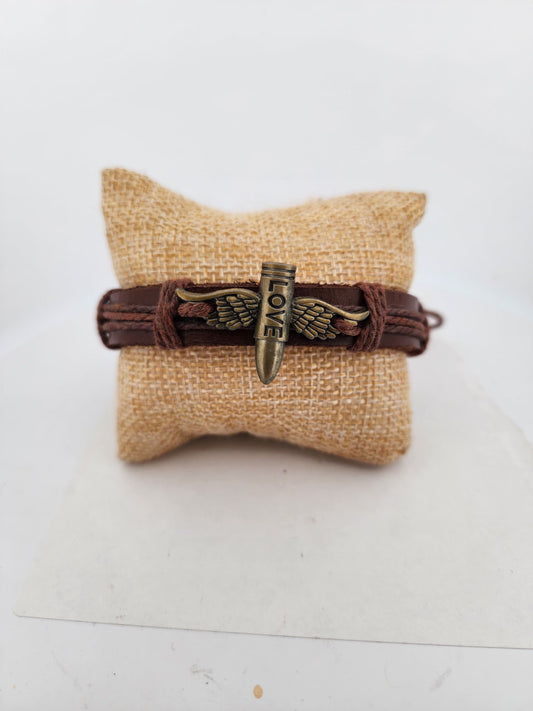 Brown leather bracelet with a decorative charm on a burlap pillow against a white background
