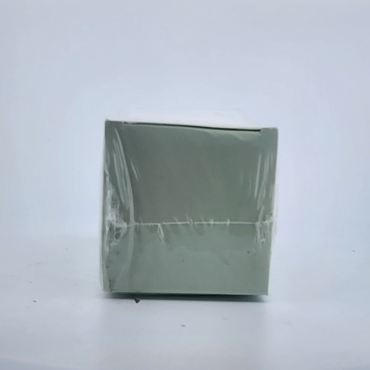 Green square object with clear plastic wrap on a white background