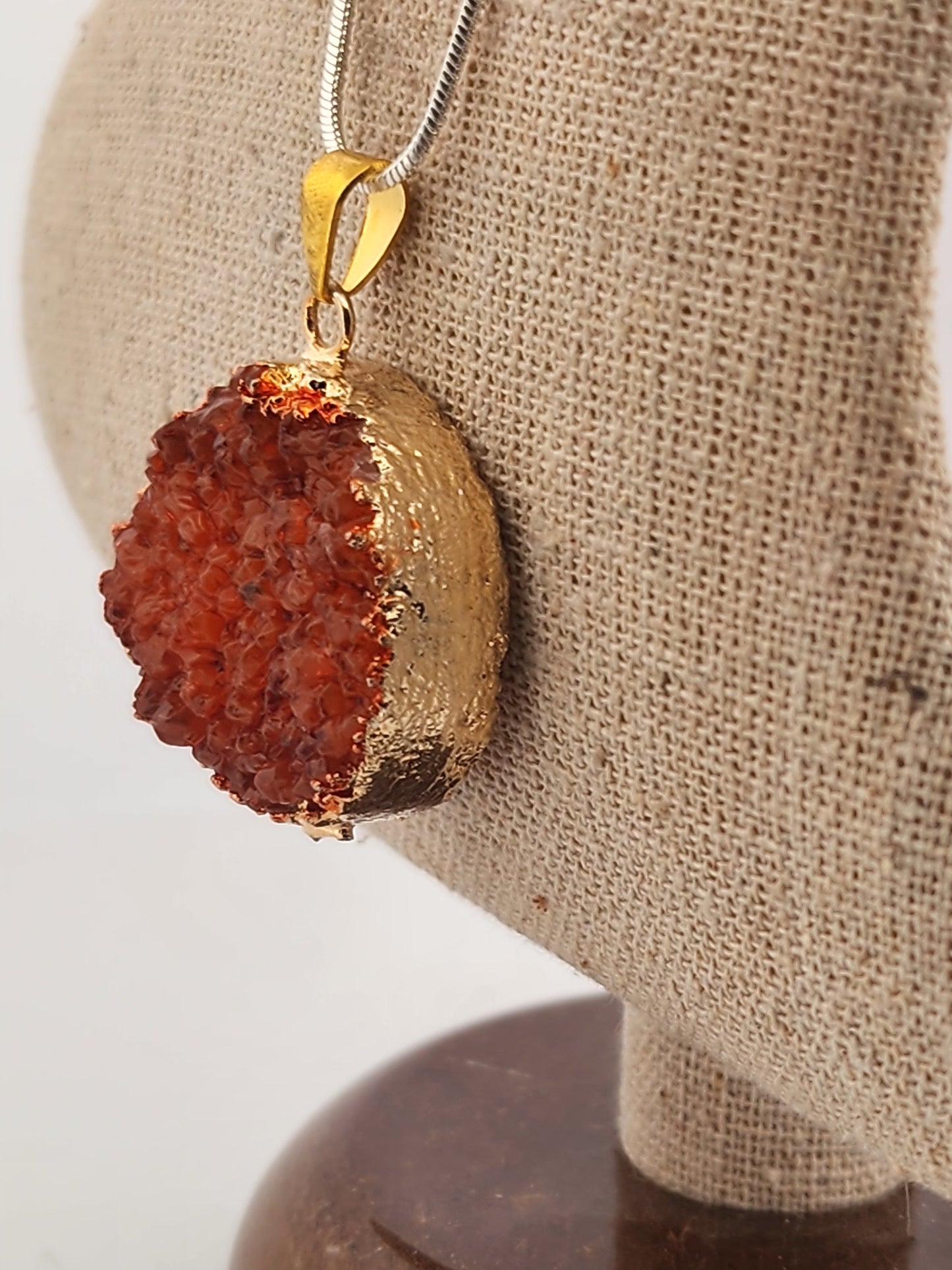 Gold pendant with a red stone on a beige fabric background