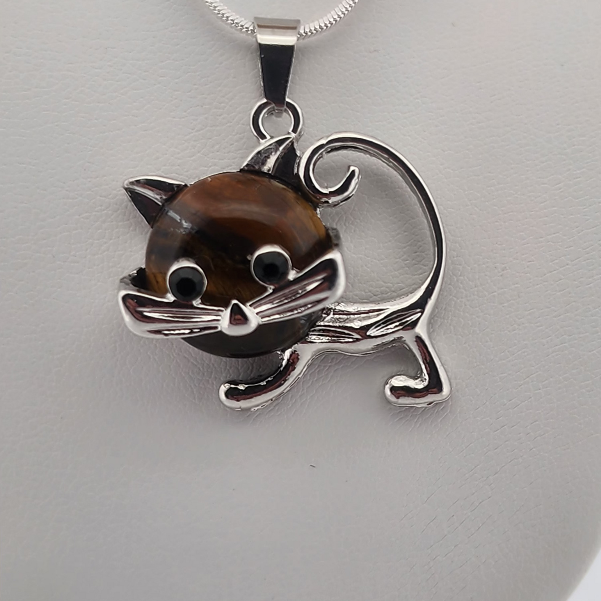 Silver necklace with a cat pendant on a white stand against a white background