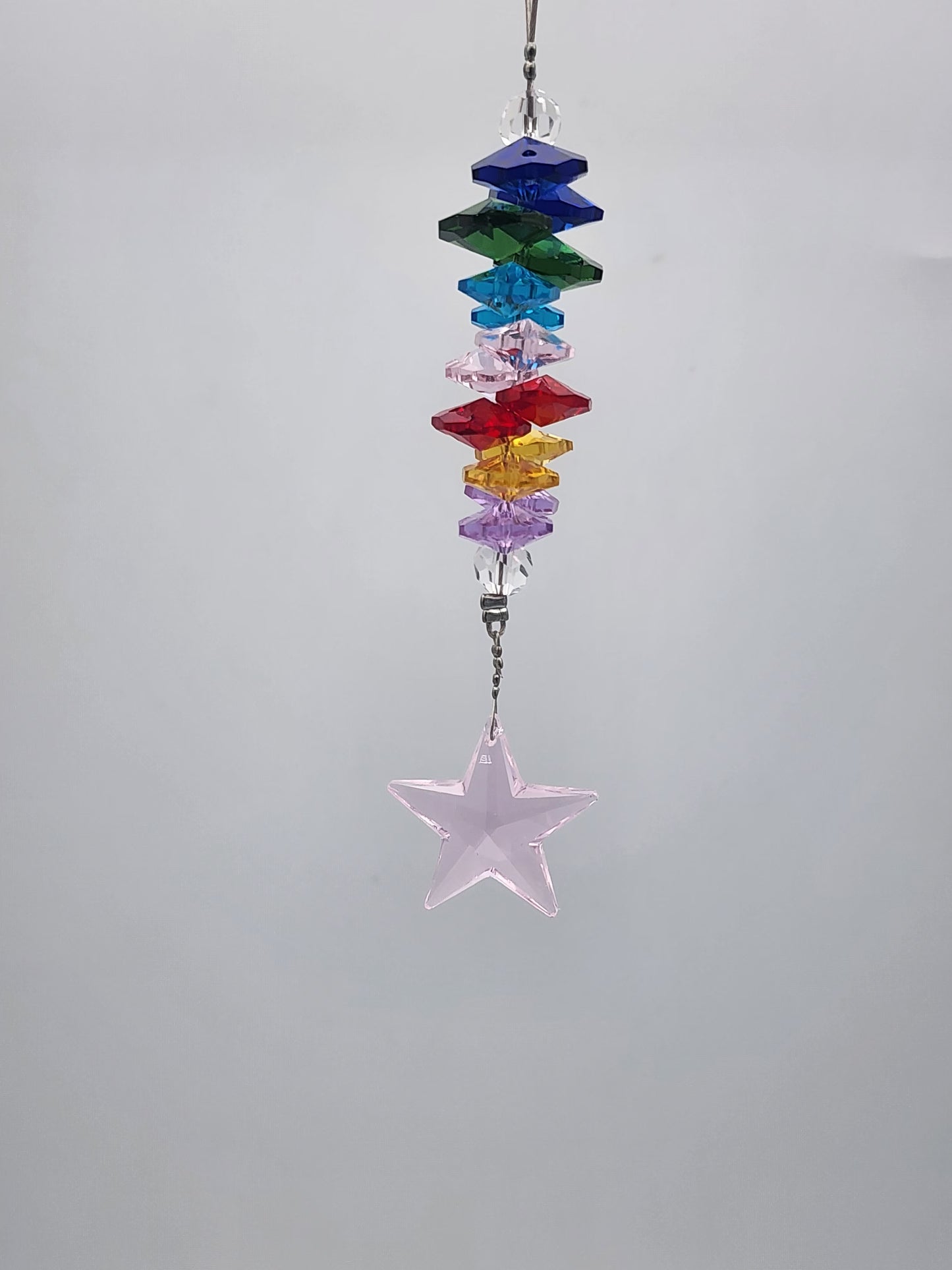 Colorful beaded hanging ornament with a star-shaped crystal on a gray background