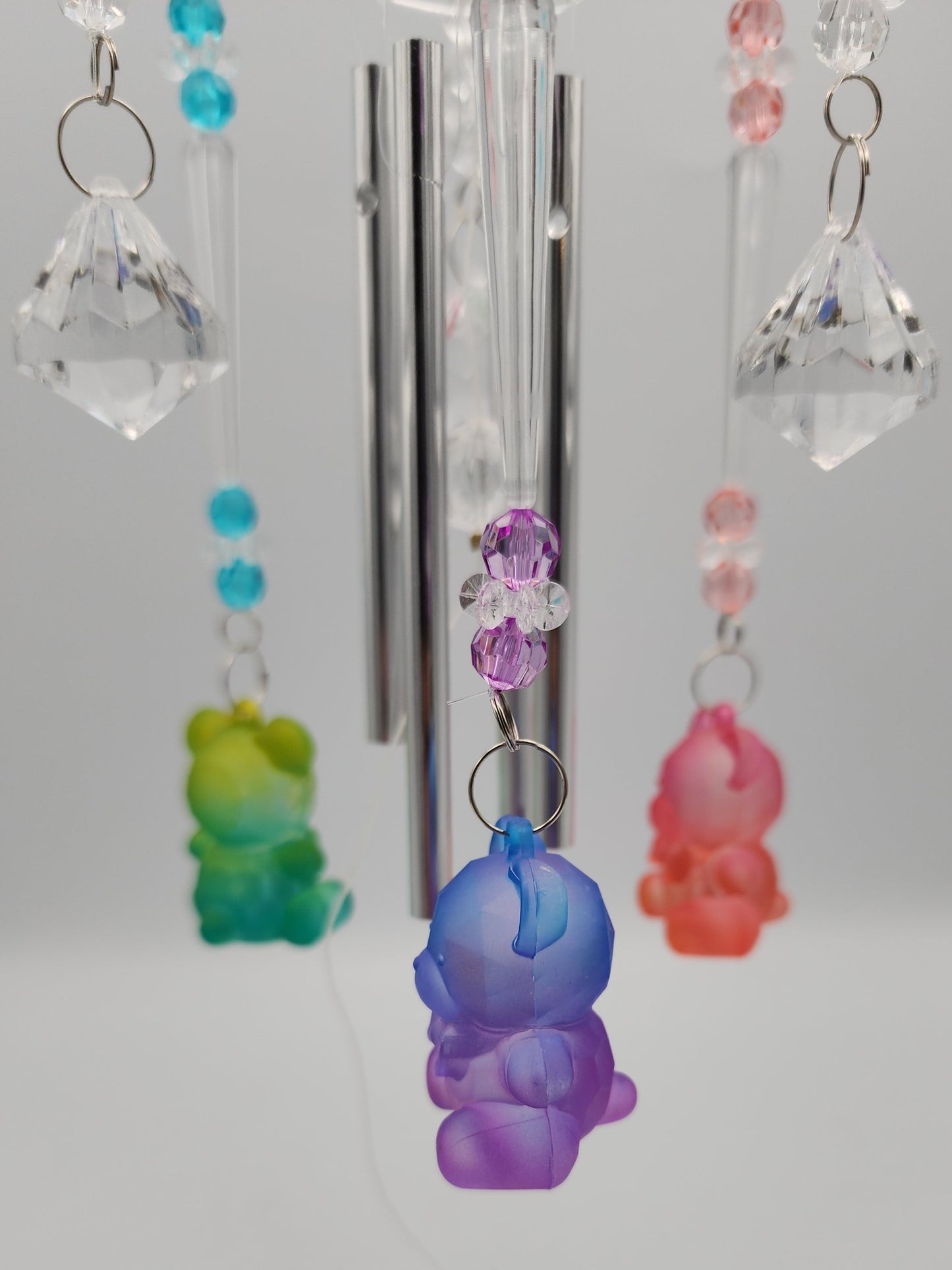 Colorful keychain charms with crystals hanging on a metal rod against a white background