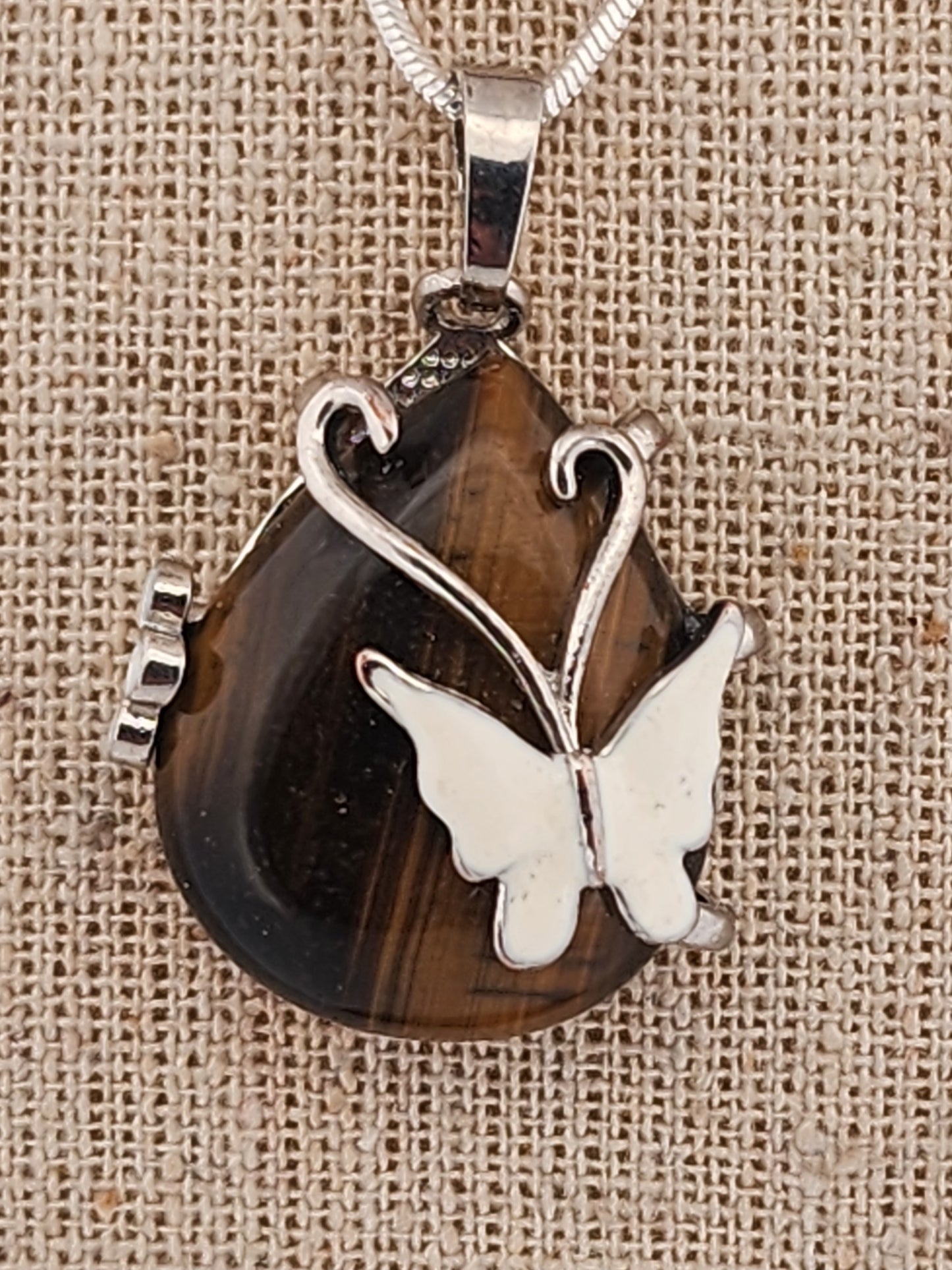 Butterfly pendant on a brown stone with silver accents on a beige fabric background