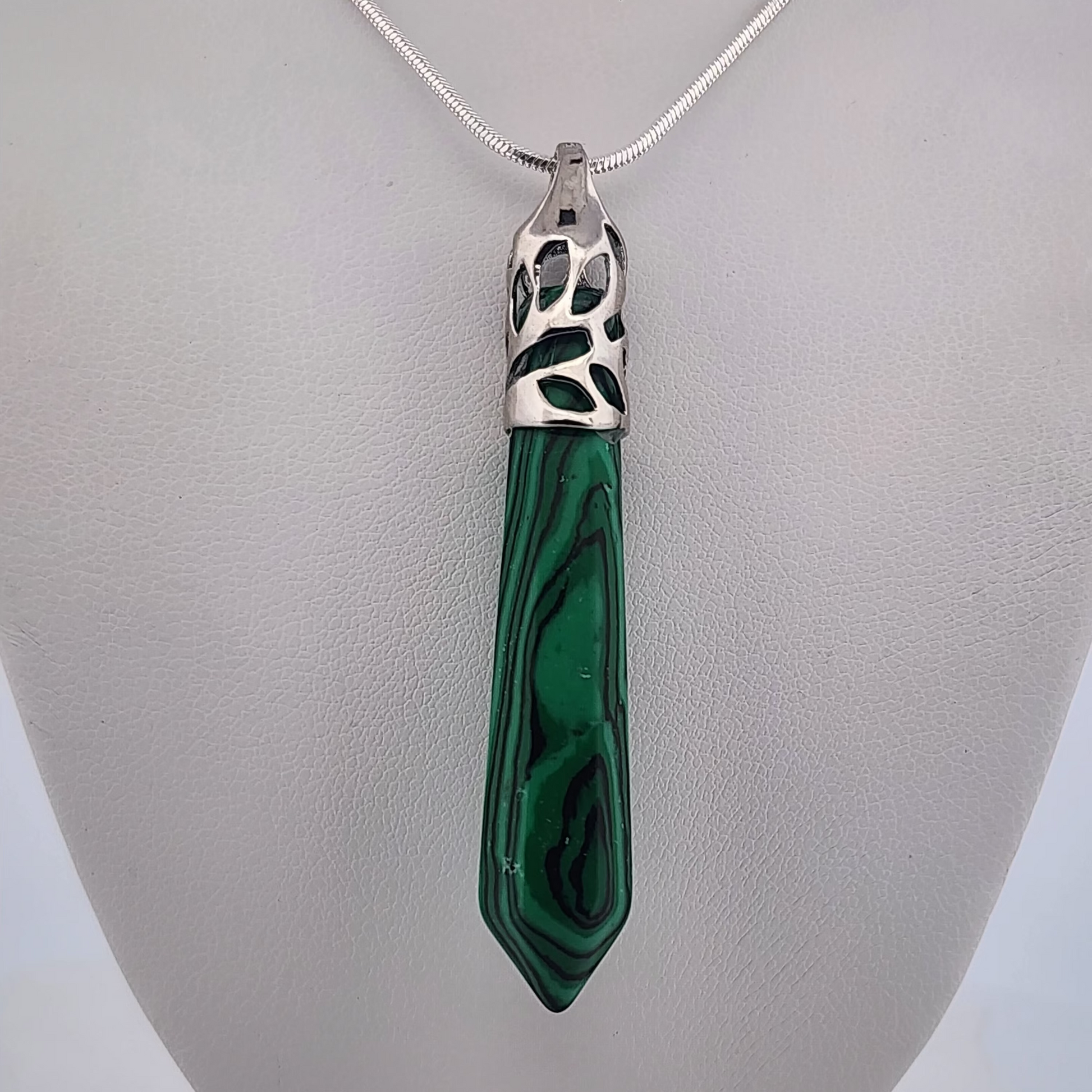Green malachite pendant on a silver chain against a gray background