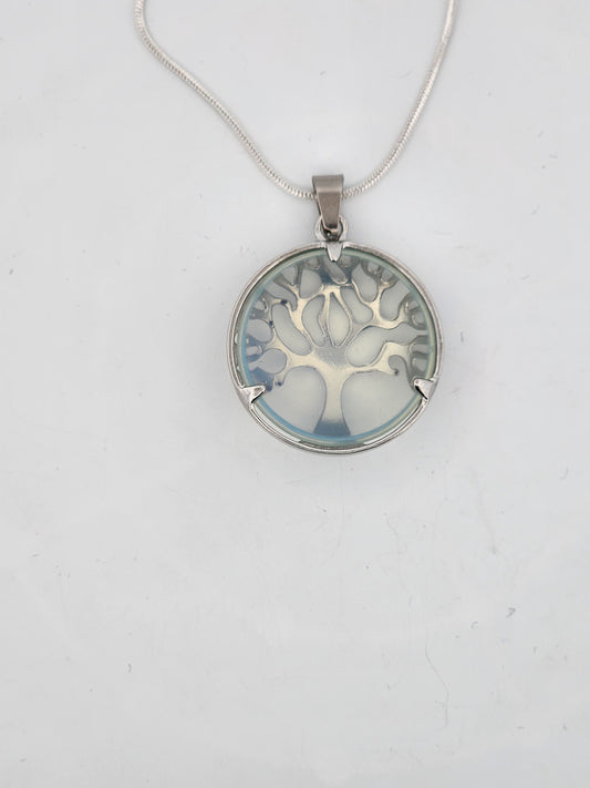 Round silver pendant with tree design on a white background