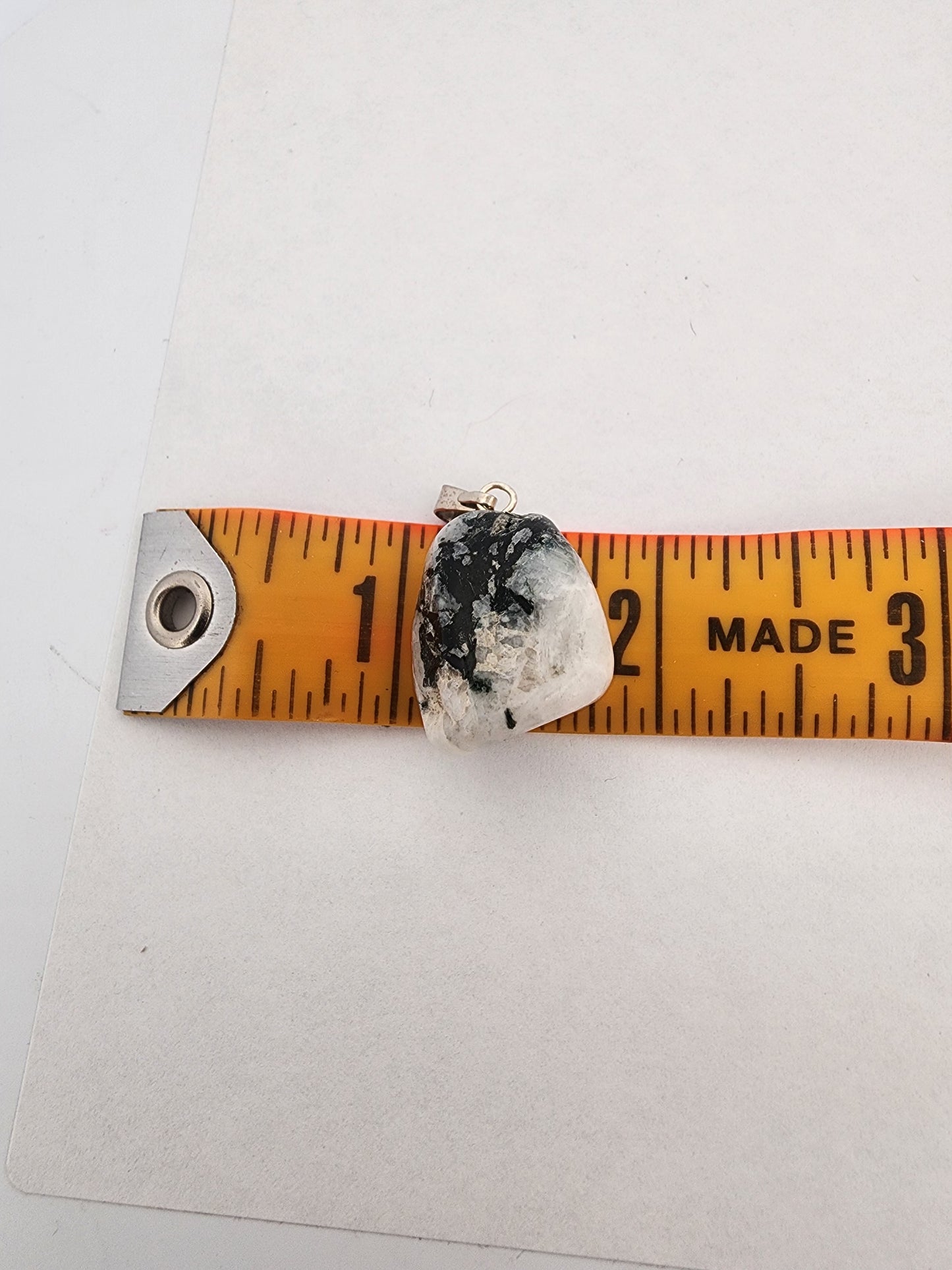 Crystal pendant on a ruler for size measurement against a white background