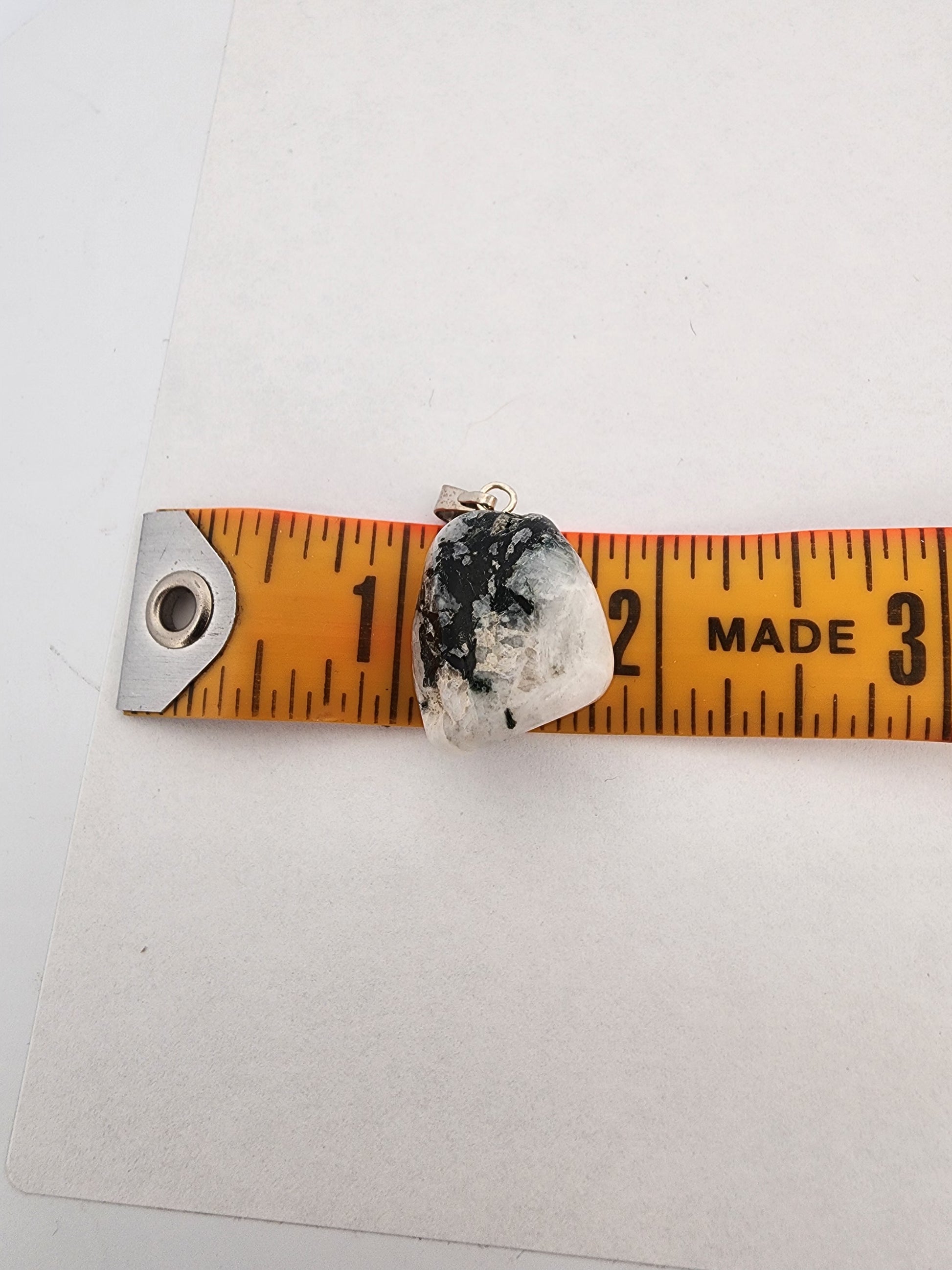 Crystal pendant on a ruler for size measurement against a white background