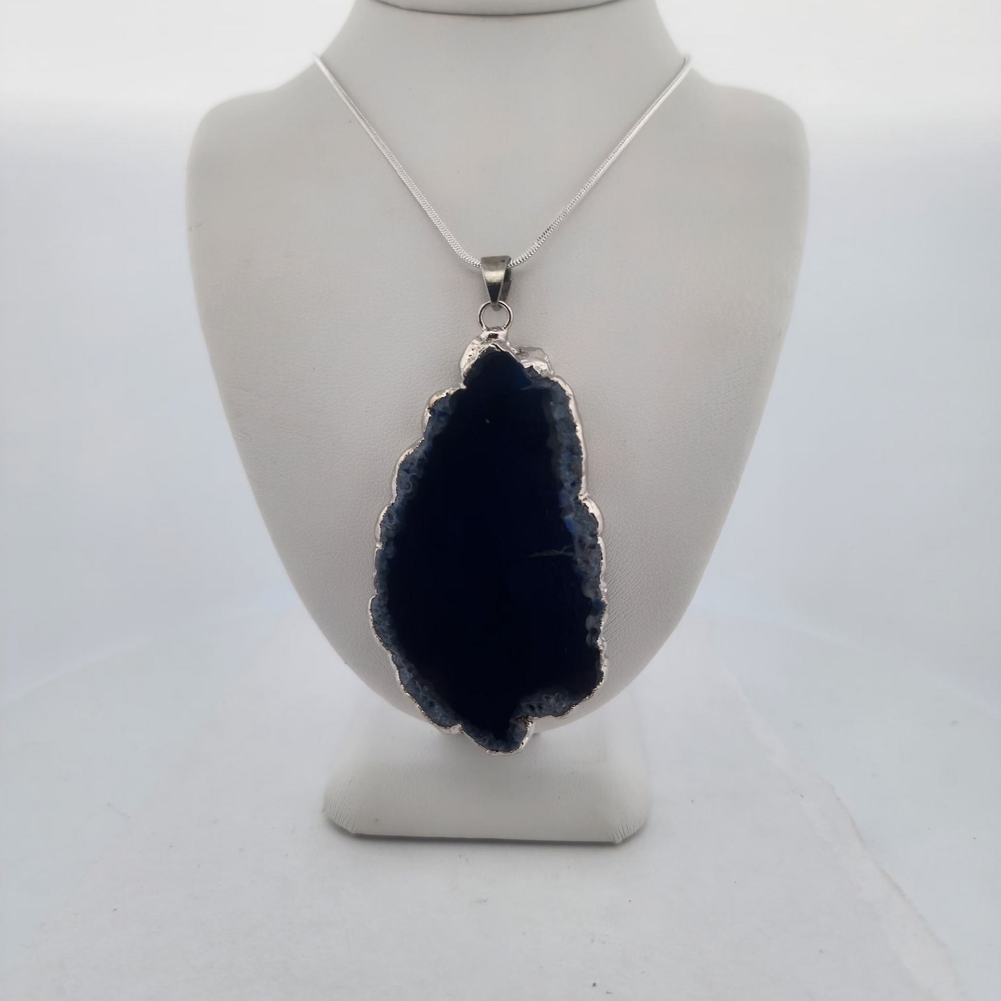 Navy blue stone pendant on a white mannequin bust against a white background