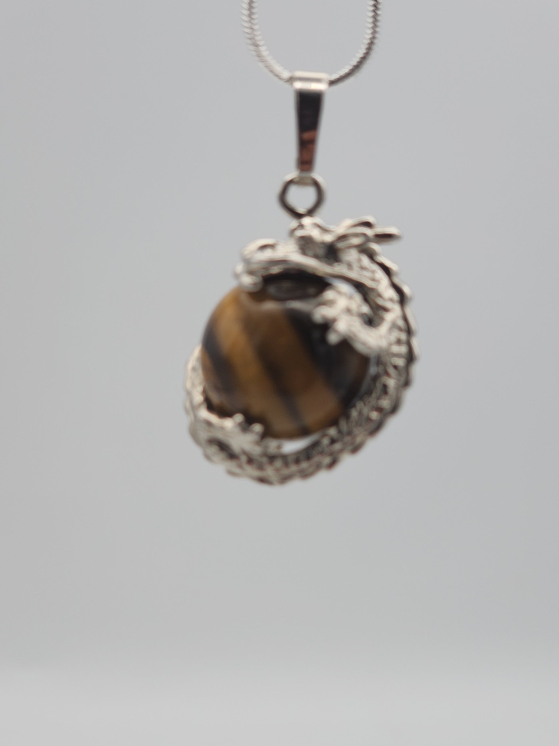 Silver pendant with a tiger's eye stone on a gray background