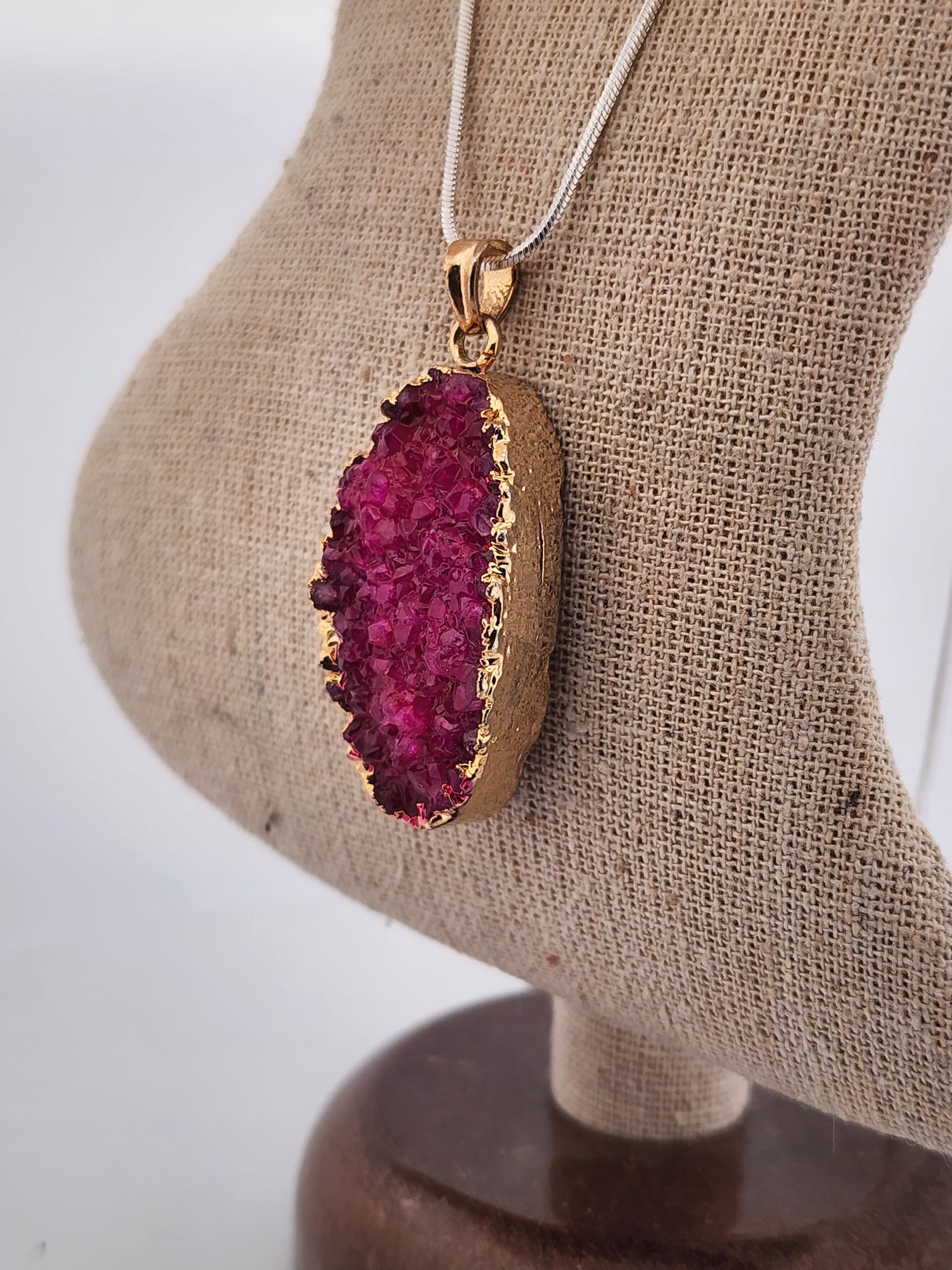 Necklace with a pink geode pendant on a mannequin bust.