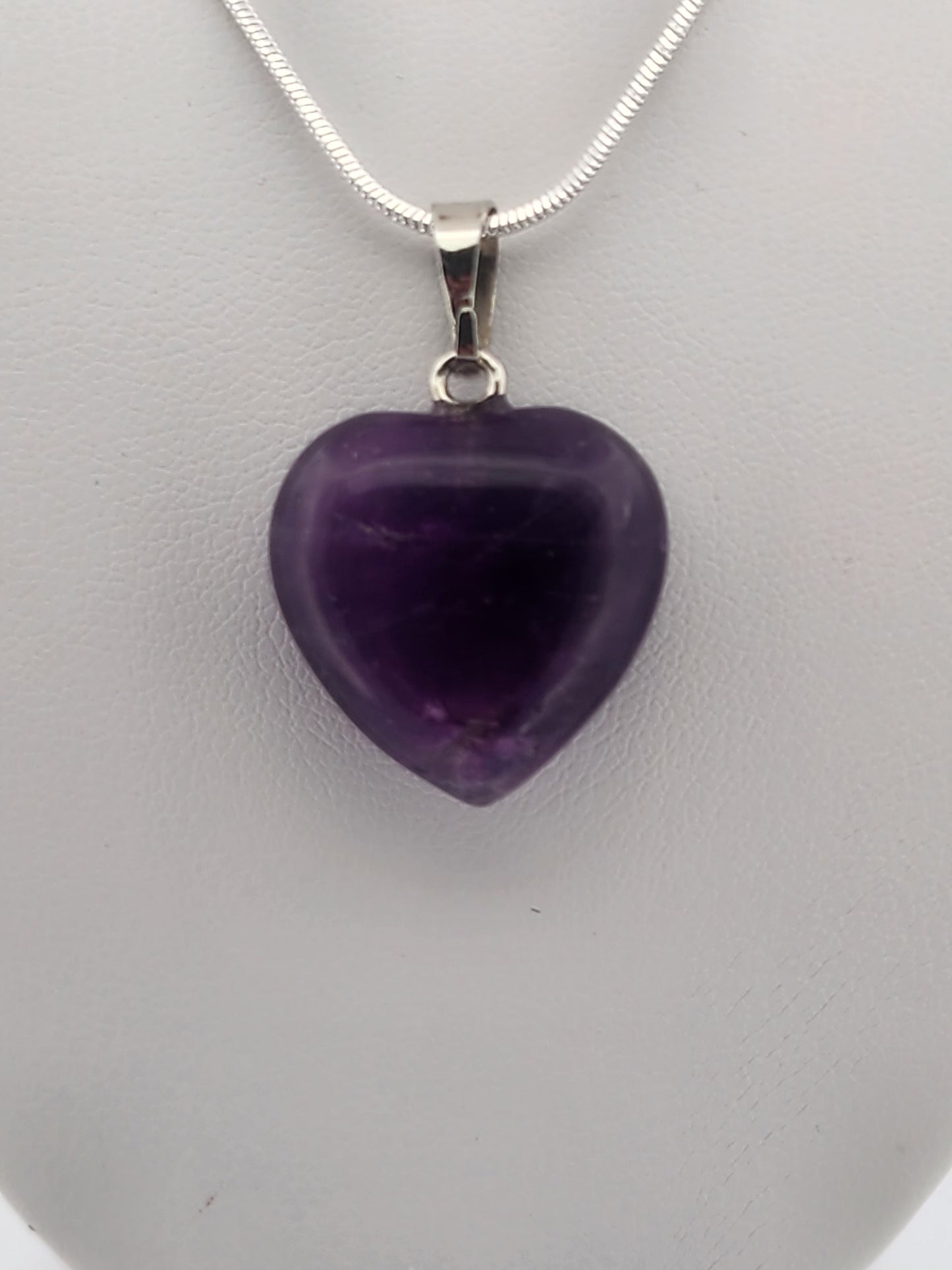 Necklace with a purple heart pendant on a gray mannequin bust against a white background