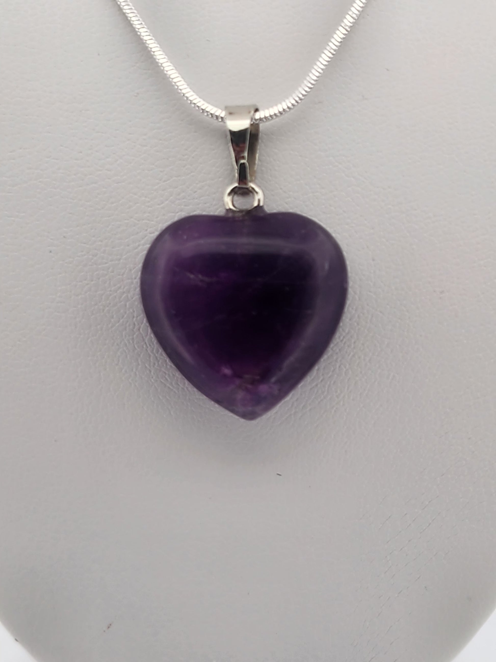 Necklace with a purple heart pendant on a gray mannequin bust against a white background
