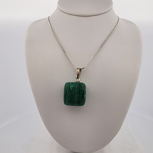 Green pendant on a silver chain displayed on a white bust