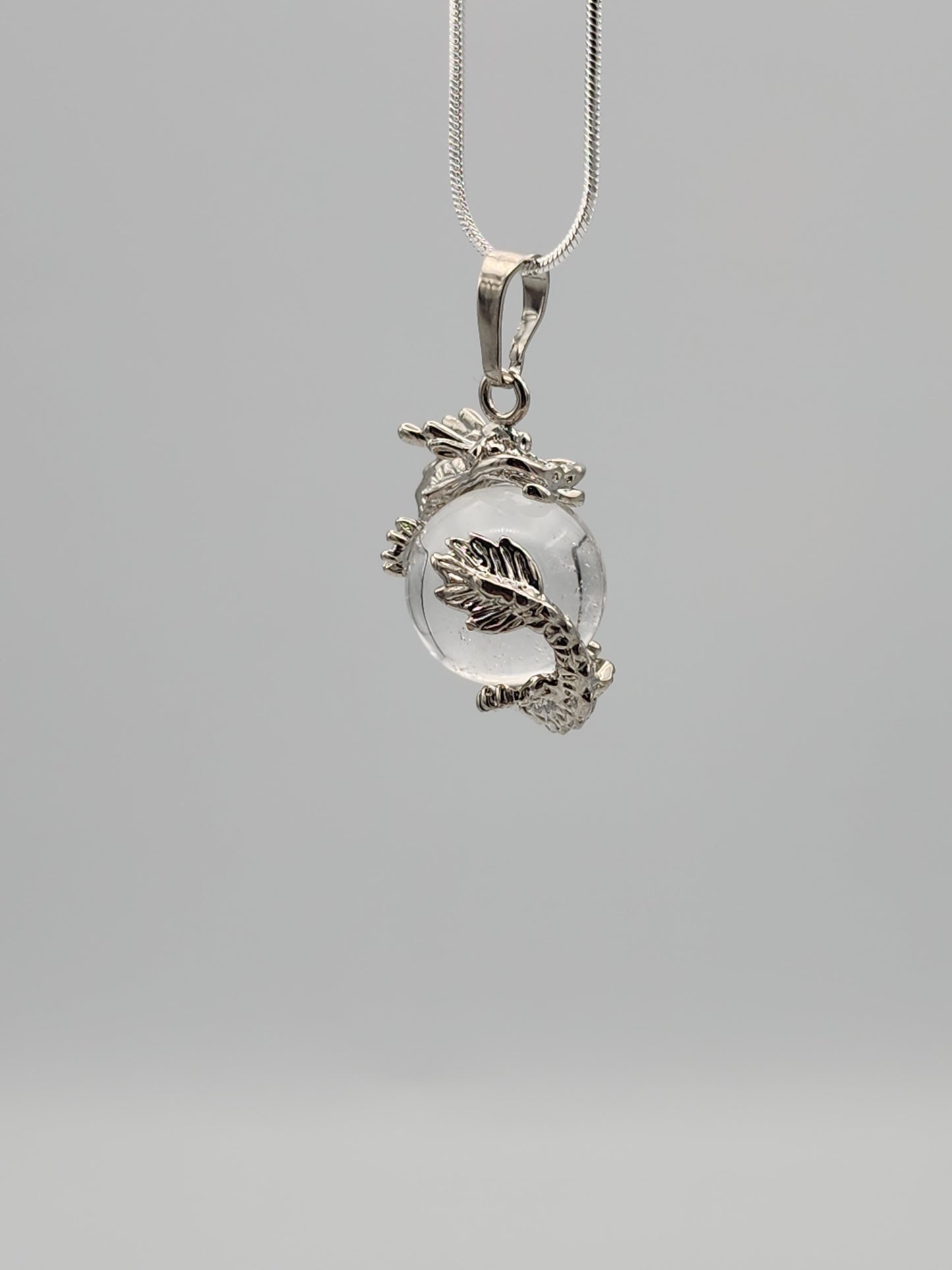 Silver pendant with a clear stone on a gray background