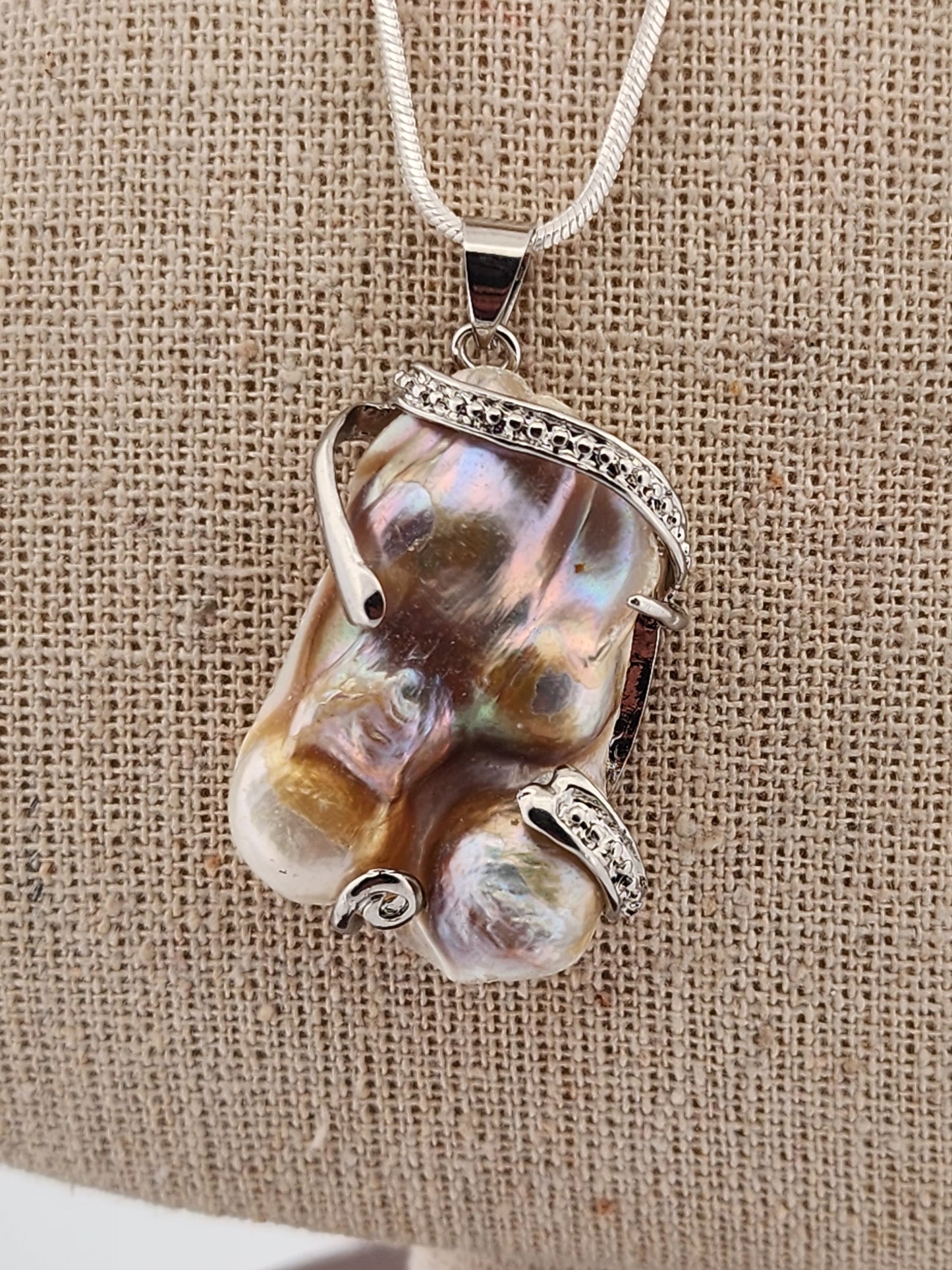 Pearl pendant necklace on a textured beige background