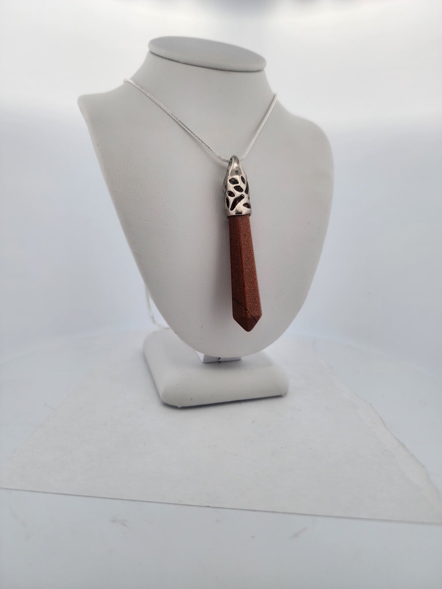 Necklace with a brown pendant on a white bust against a white background