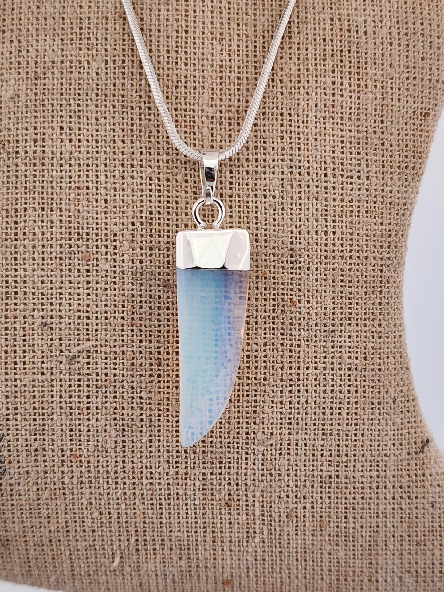 Necklace with a blue and silver pendant on a textured brown background